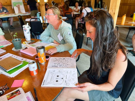two teachers at a training looking at a owl activity book