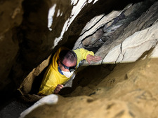 biologist wearing protective equipment and a head lamp surveying a bat cave