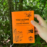 An orange book titled, "You Alone in the Maine Woods"