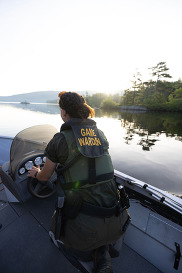 game warden driving a boat on calm lake