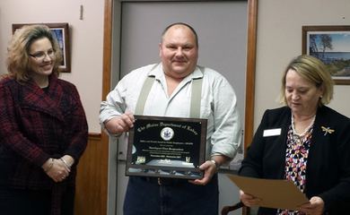 Hank Lang (center) receives the SHAPE Award for Northport First Responders from Pamela Megathlin (left), Director, Bureau of Labor Standards, as Dorot