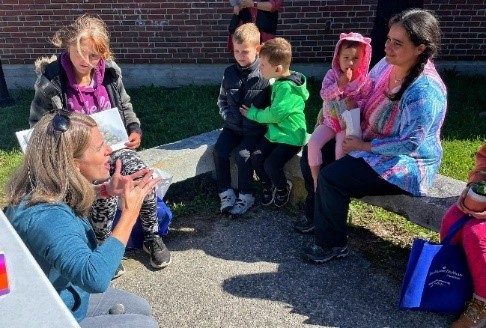 This is a graphic showing  Children sitting outside at the Deaf Culture Festival