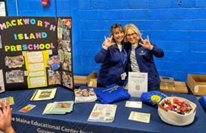 This is a picture of Two friends making the “I Love You” sign at the Mackworth Island Preschool exhibit.