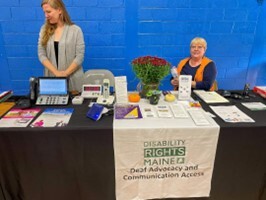 This is a picture of Two friends at the Disability Rights Maine Deaf Advocacy and Communication Access exhibit.