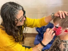 This is a picture of an Adult face painting a child.