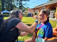 Regan Thibodeau face painting a child