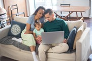 Two people and one child sitting on a couch with a laptop