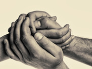 Protecting Our Elders - Mans hands holding elder female hands on isolated, toned background. 