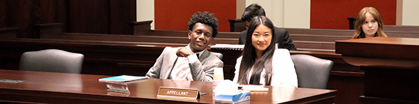 Two smiling teen participants sitting in the Michigan Supreme Court courtroom.