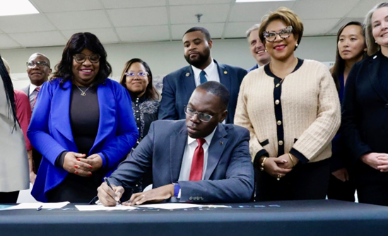 LT Governor Gilchrist sitting behind a desk signing legislation