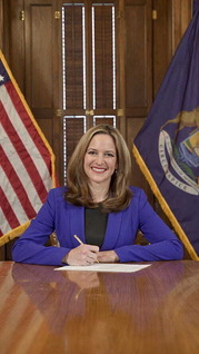 Acting Governor Benson signing a bill behind a desk