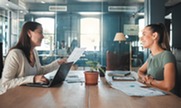 Two women sitting across the table from one another in a job interview