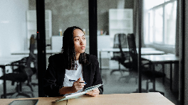 woman sitting at a desk in an office looking out a window