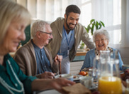 nursing home worker smiling and talking to residents seated around a table