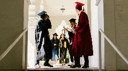 high school graduates in caps and gowns mingling in a hallway