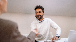 man shaking hands with someone across a table