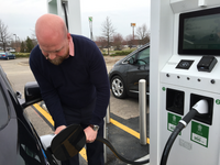 An electric vehicle driver uses a fast-charger at a Walmart in Lansing, Michigan