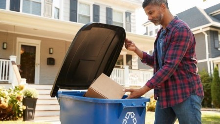 Person placing cardboard into recycling bin