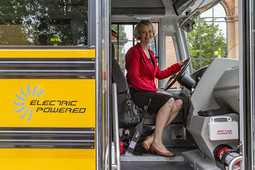 EGLE Director Liesl Clark at the steering wheel of an electric school bus at event in 2019.