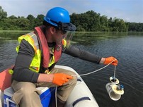 An EGLE staffer takes a water sample from the Huron River after a hexchrome release.