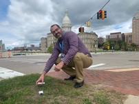 EGLE staffer Bryan Grochowski picks up litter in the shadow of the Capitol Building.