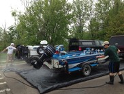 Two students and mobile boat wash crew members clean a boat at Lake Ovid.