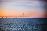 Photo of the Mackinac Bridge and the Straits of Mackinac with a hazy, redish sky.