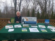 Bob Ripstra sitting at a table with Hess Lake and Shoreland Stewards information. Photo courtesy of Bob Ripstra.