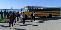 EGLE Director Phil Roos and others with Pellston School District's new electric school bus with the Mackinac Bridge in the background.