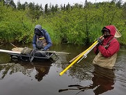 EGLE staff carry water, fish, and aquatic insect sampling equipment into the Shelldrake River.