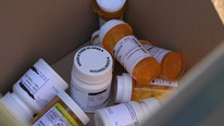 Prescription bottles collected in a box in preparation for Take Back Day pill recycling.