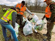 Jon Walt, Chris Bowen and Lt. Vence Woods put trash in bags along I-75 near Gaylord, with Deb Woods in the background.