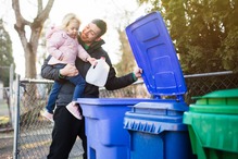 Child places milk carton into recycling cart. 