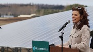 Governor Gretchen Whitmer at lectern with MI Healthy Climate Plan sign and a solar panel in the background. 