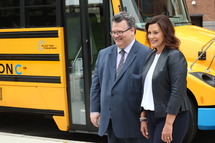 Gov. Whitmer stands with Eric Marquis, in front of a Lion Electric Co. school bus.