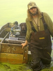 Man deploys decoys with his chocolate lab in preparation of a duck hunt. Courtesy DNR. 