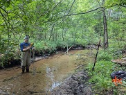 EGLE Aquatic Biologist Joshua Tellier uses monitoring equipment to measure streamflow.