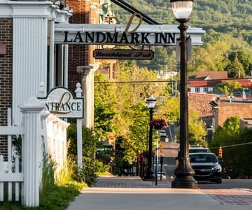 Landmark Inn sign by entrance, along brick street with trees in the background