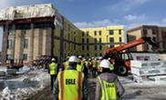 State and others in yellow safety vests tour the Cadillac Lofts brownfield redevelopment.