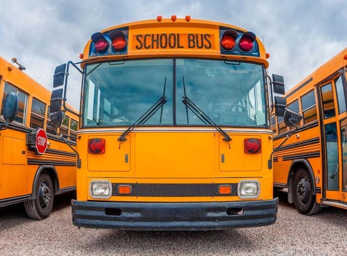 A picture of a school bus with busses beside it.