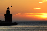 a picture of a lighthouse on the edge of a lake