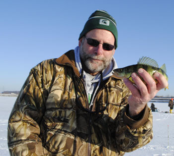 Angler holds up a yellow perch caught through the ice