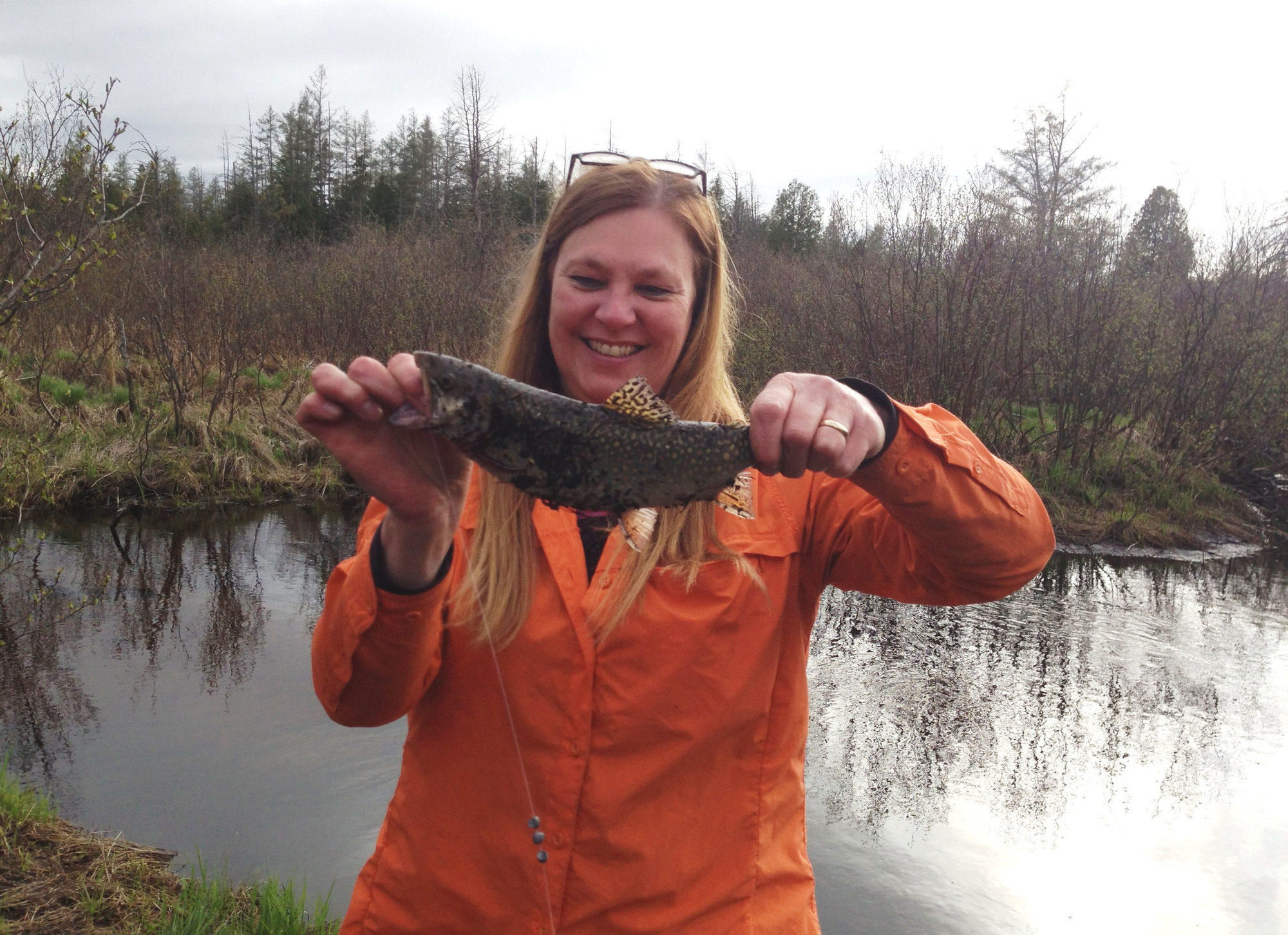 Cathy Pederson, at a stream, with a nice brookie she caught on an early season trip.