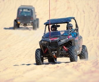 Two ORV riders riding in the sand.