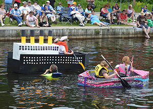 Day on the Canal with kids in cardboard boats and people watching.