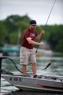 Man on boat reels in a bass