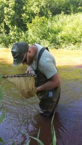 MSU student holding a net while sampling for crayfish