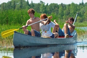 three teenagers paddling in a canoe