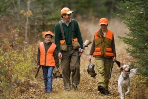father and two daughters walking through woods after bird hunting