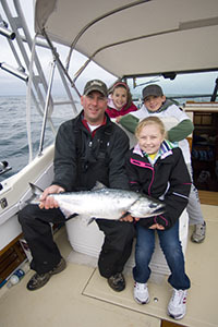 Youth and adult holding Chinook salmon on charter boat